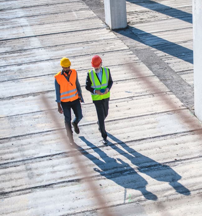 Two i-GlooAdvance engineers walking across a concrete work site